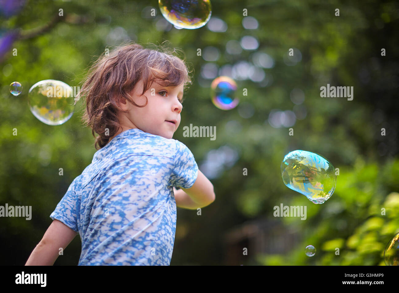 Girl waving bubble wand in garden Stock Photo