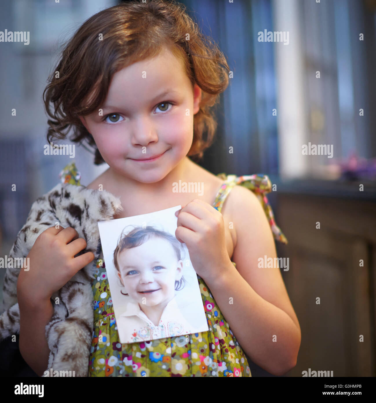 Portrait of girl holding photograph of herself Stock Photo