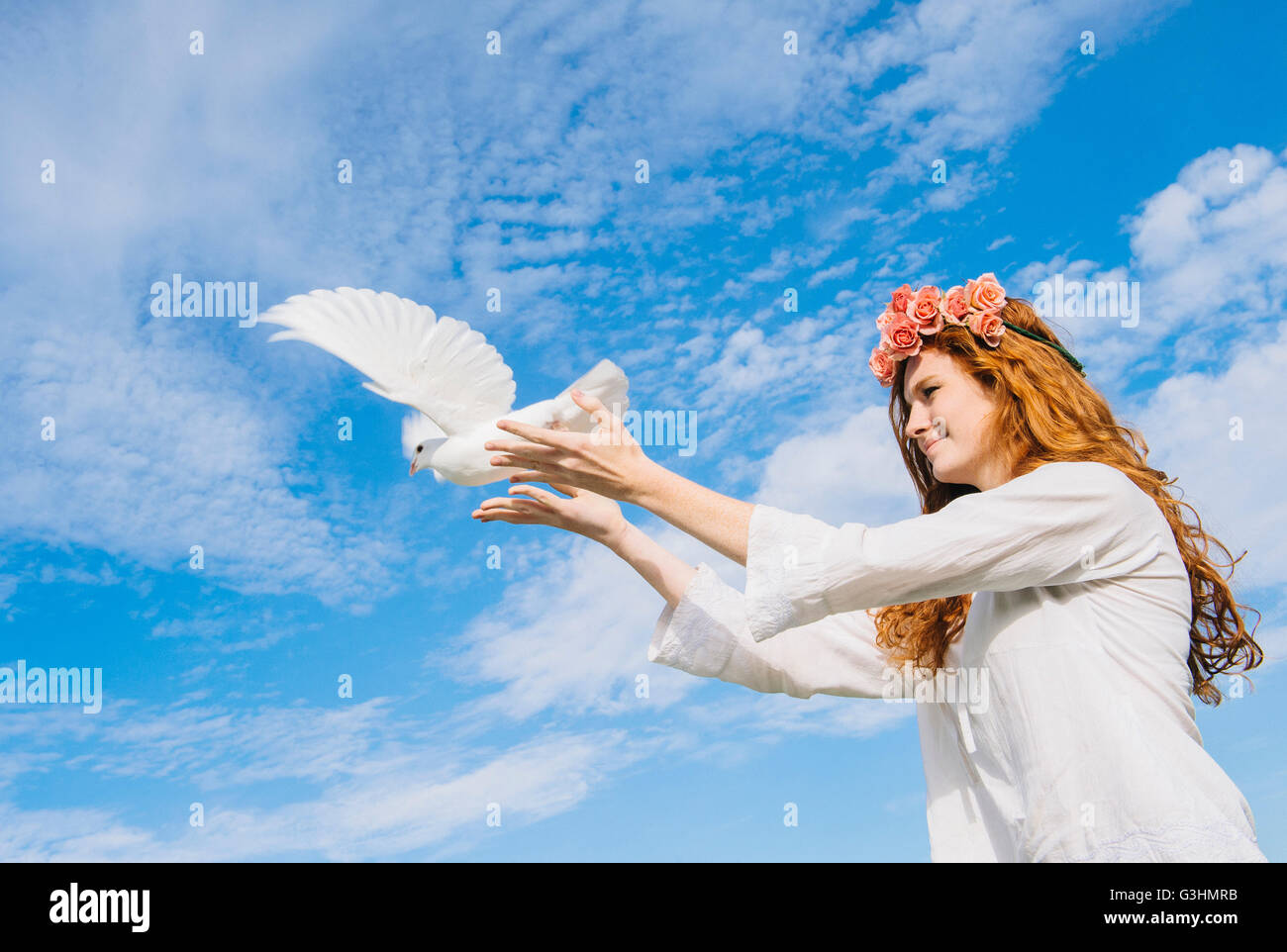 Teenage girl releasing white dove into sky Stock Photo