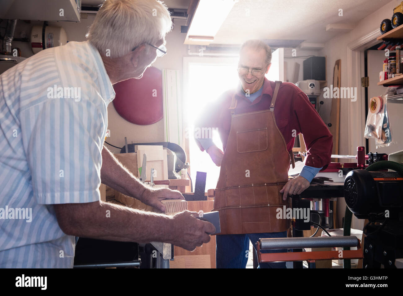 Senior men sanding woodblock in carpentry workshop Stock Photo