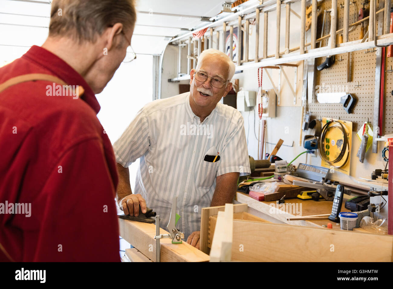 Senior men planing woodblock in carpentry workshop Stock Photo