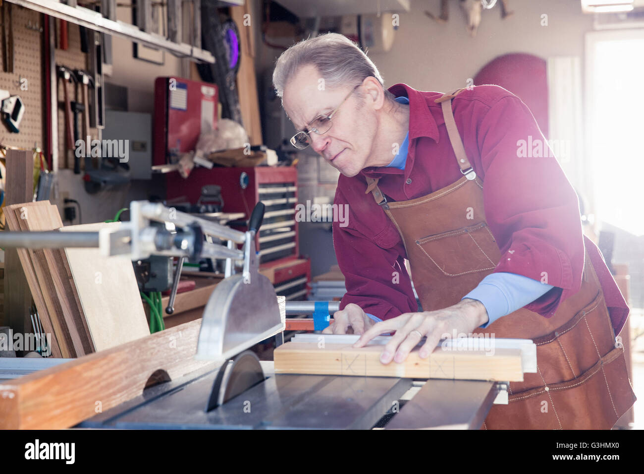 Senior man sawing woodblock in carpentry workshop Stock Photo