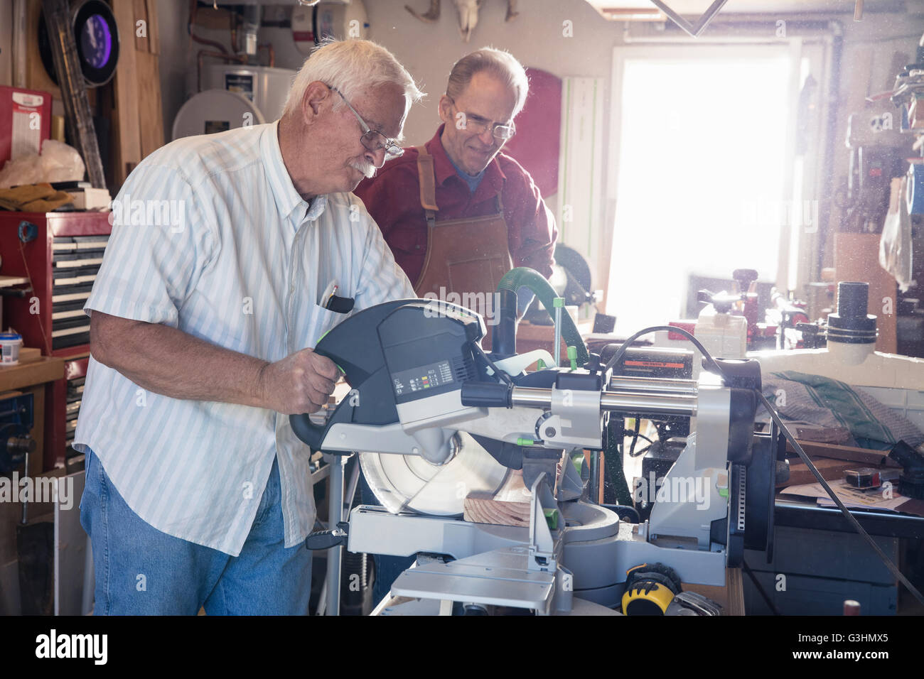 Senior men sawing woodblock in carpentry workshop Stock Photo