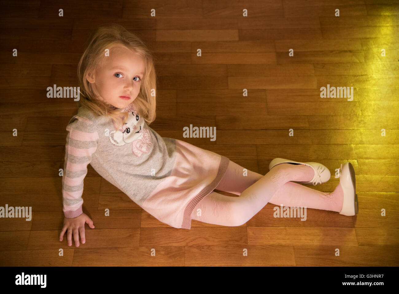 Blond girl sitting on wooden floor in the house Stock Photo - Alamy