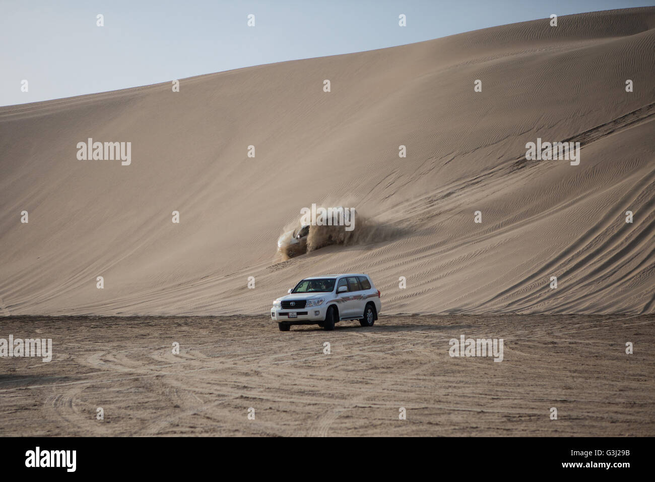 4 x 4's driving over sand dunes in the desert in Qatar. Arabian