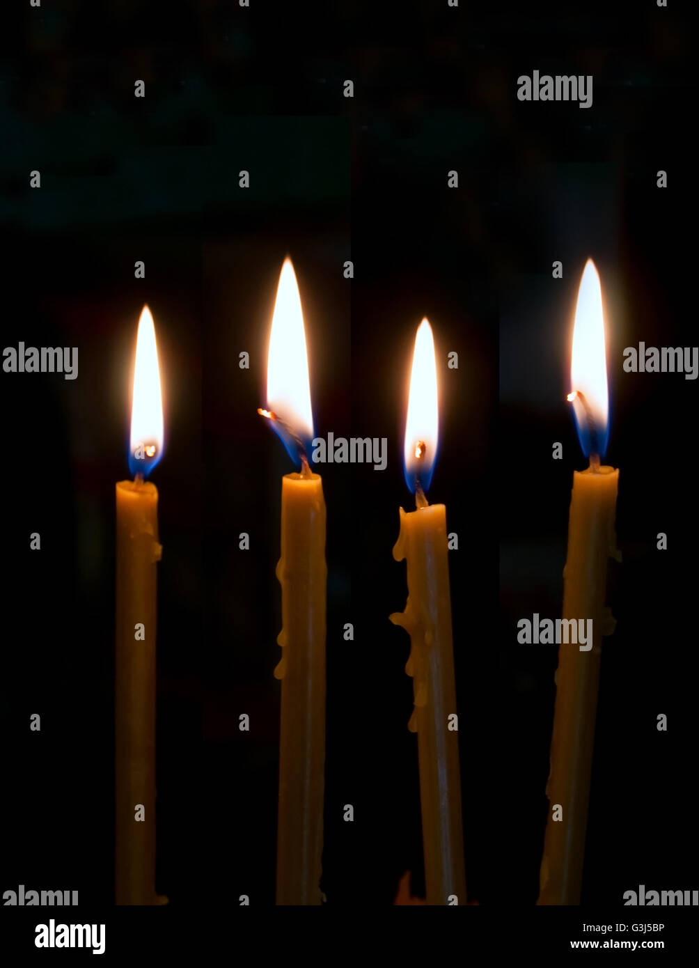 four alight candles over the black background Stock Photo - Alamy