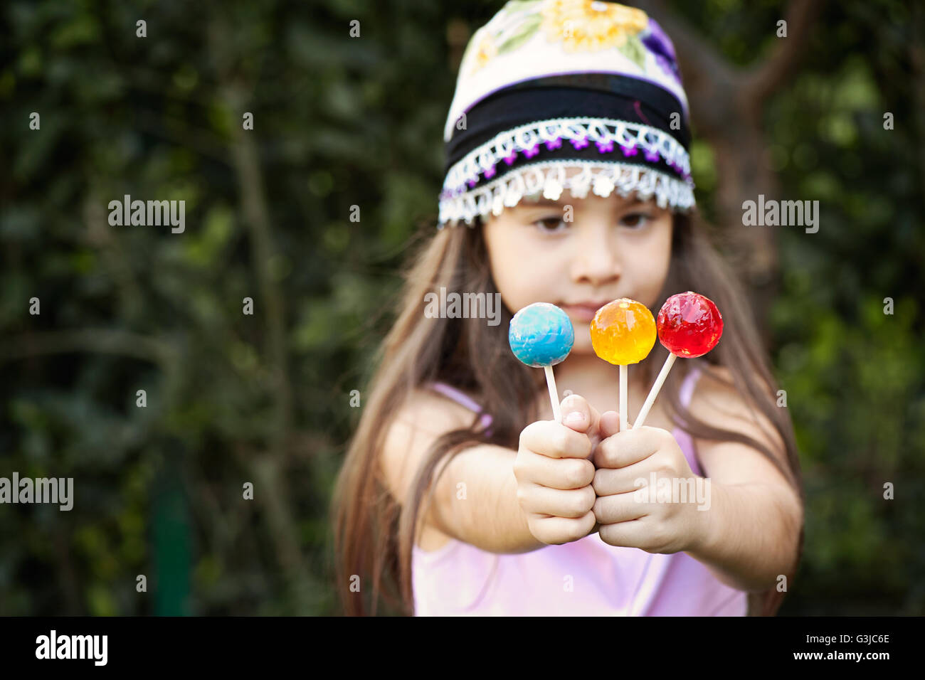 Small girl with  lollipops in each hand Stock Photo