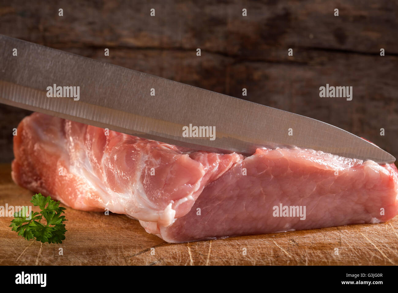 Slicing pork tenderloin with herb on wooden background Stock Photo