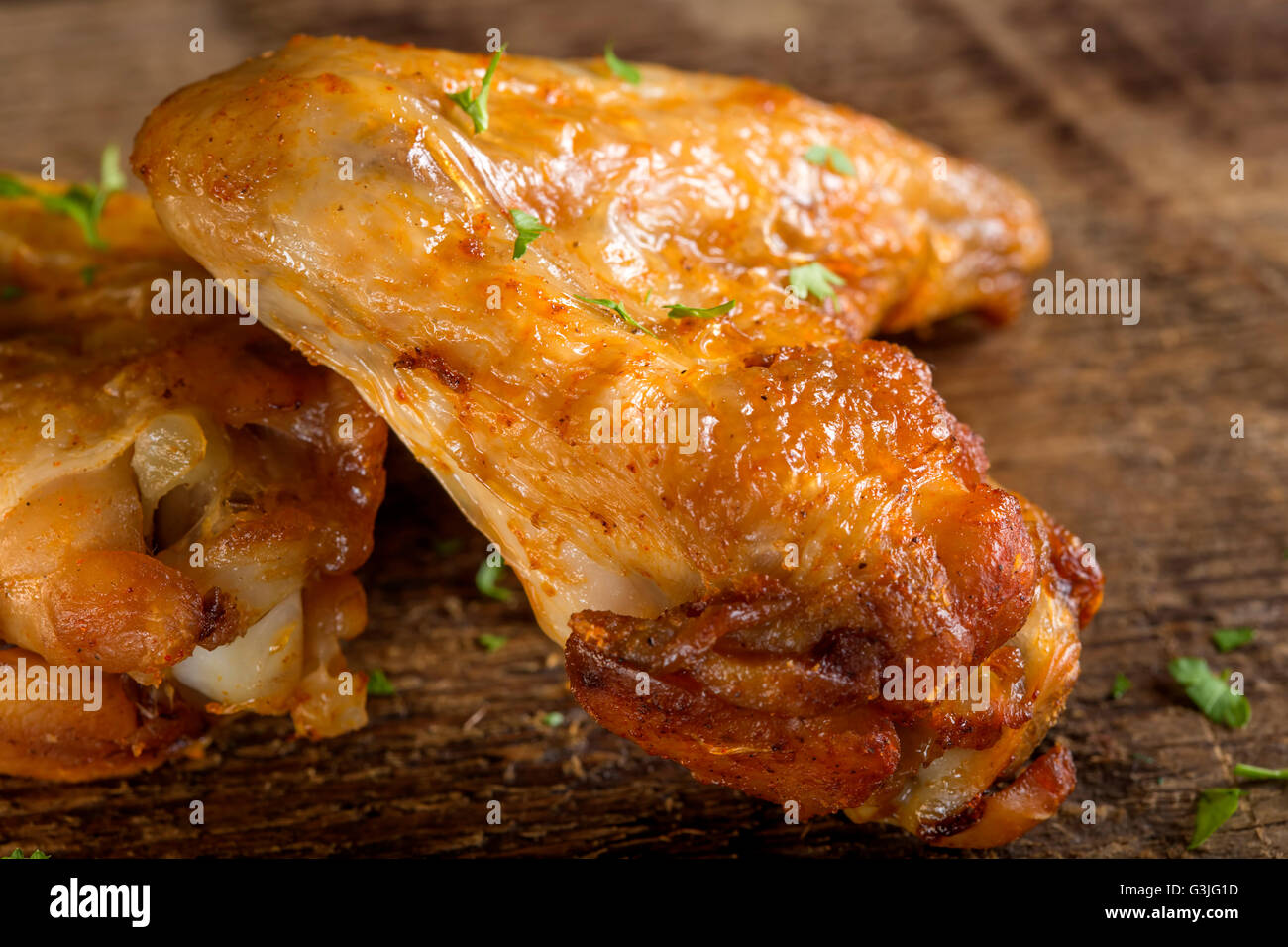 Close up of fried chicken wings on wood board with some fresh parsley Stock Photo