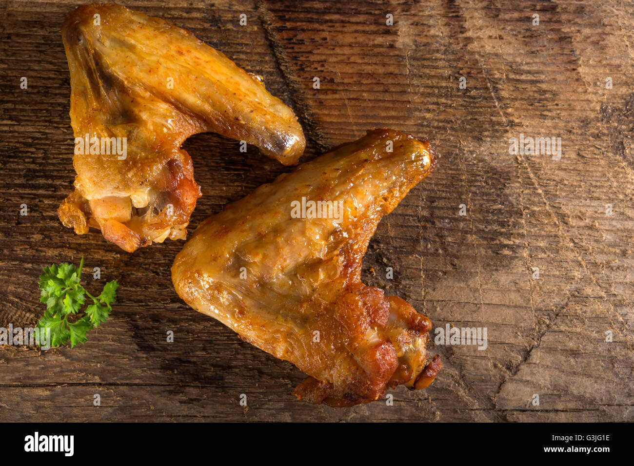 Fried chicken wings on wood board with some fresh parsley Stock Photo
