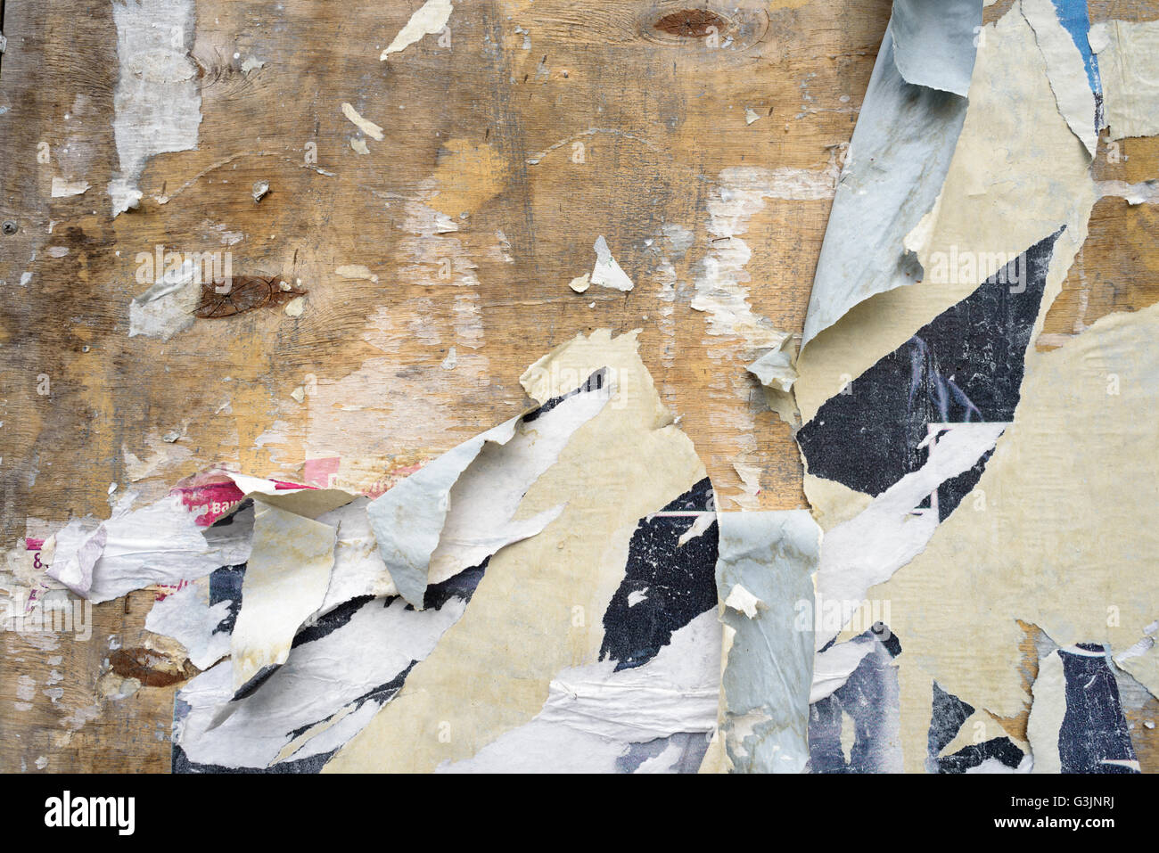 Ripped edges of a paper poster on a flat surface, showing signs of age and neglect. Grunge style background with copy space area Stock Photo