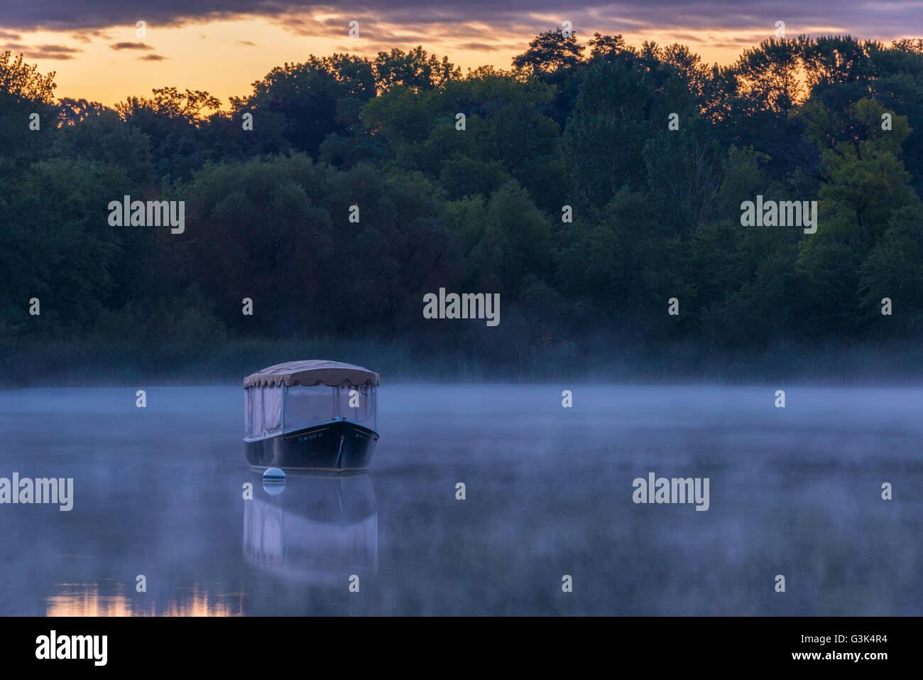 Covered boat on Lake Como, St. Paul, Minnesota at sunrise with fog rising off the lake. Stock Photo