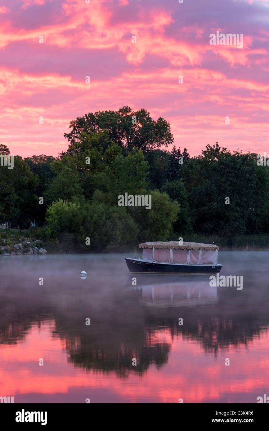 Covered boat on Lake Como, St. Paul, Minnesota at sunrise with fog rising off the lake. Stock Photo