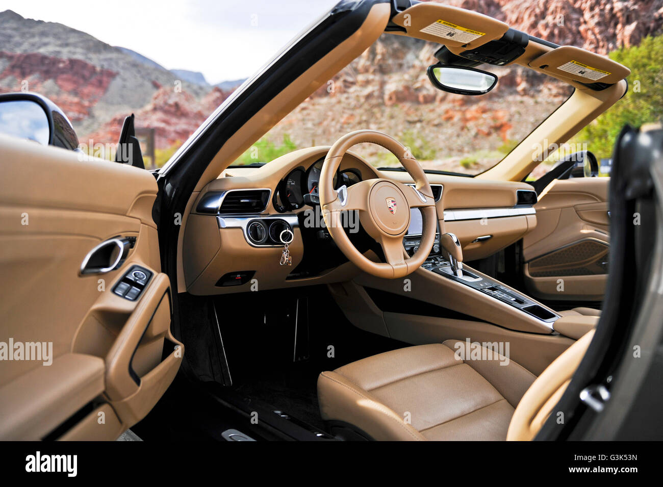 The interior dashboard, steering wheel and console of a Porsche 911 Carrera S on a desert mountain road Stock Photo