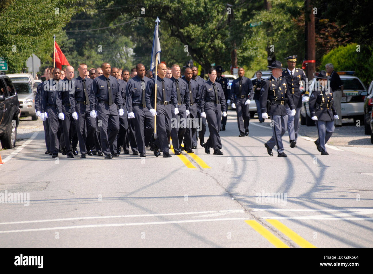 Police recruits march down the street to take a position at a policeman