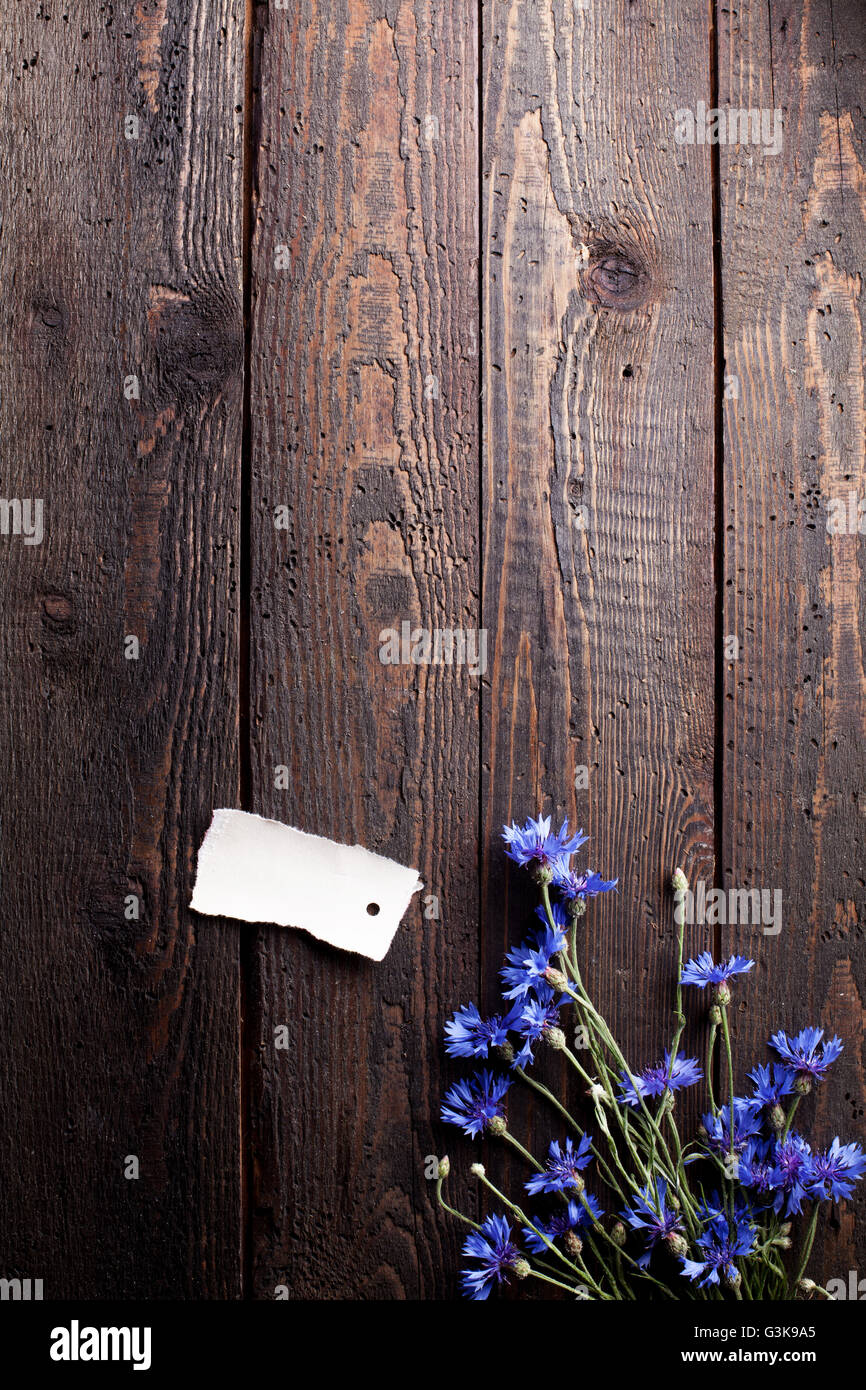 Blue cornflowers on old wood with note, flat lay Stock Photo