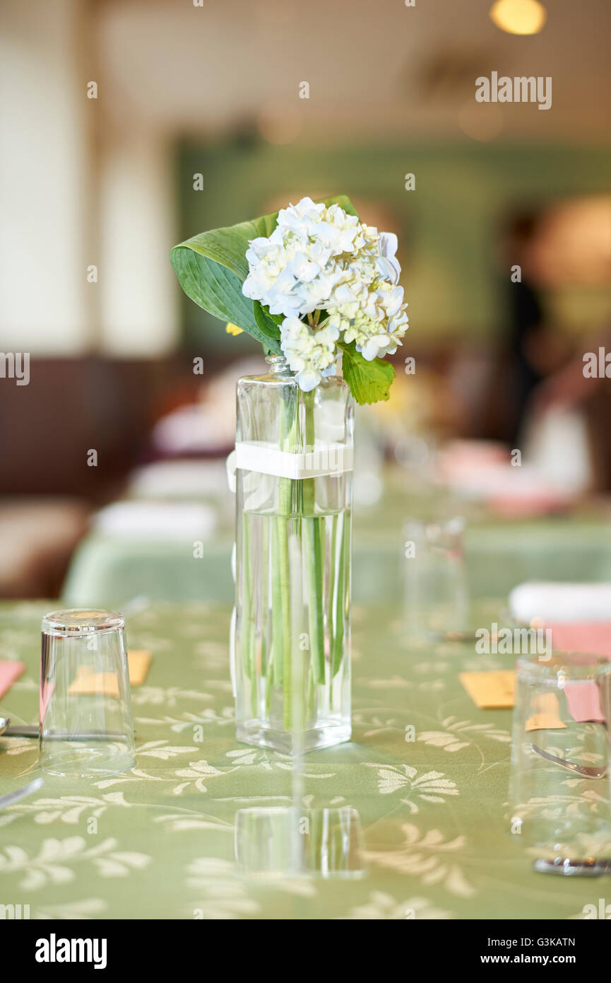 A Small Glass Vase Of White Flowers On A Green Table At A Wedding
