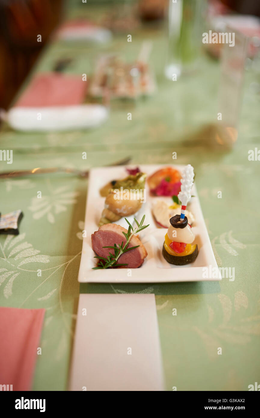A small plate of appetizers on a green table at a wedding reception with a blank name card in front. Stock Photo