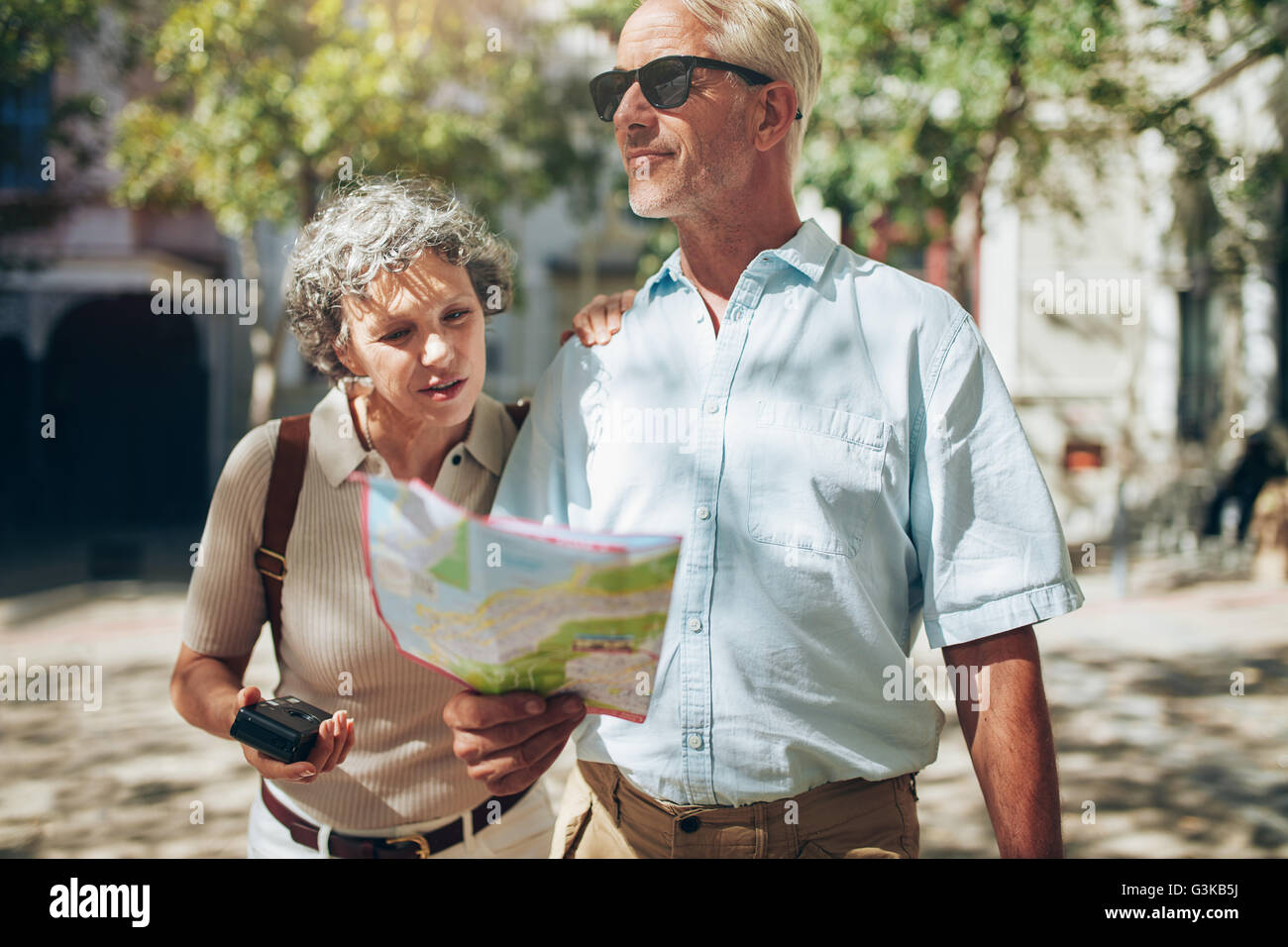 Caucasian senior couple reading a city map and looking around. Mature couple using a map on a vacation. Stock Photo
