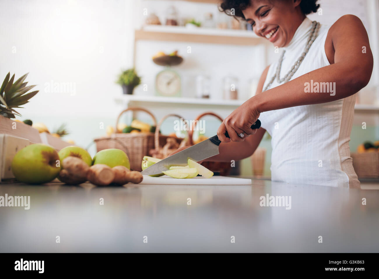 Shot of woman working at juice bar and cutting fruits. Young african woman making fresh juice. Stock Photo