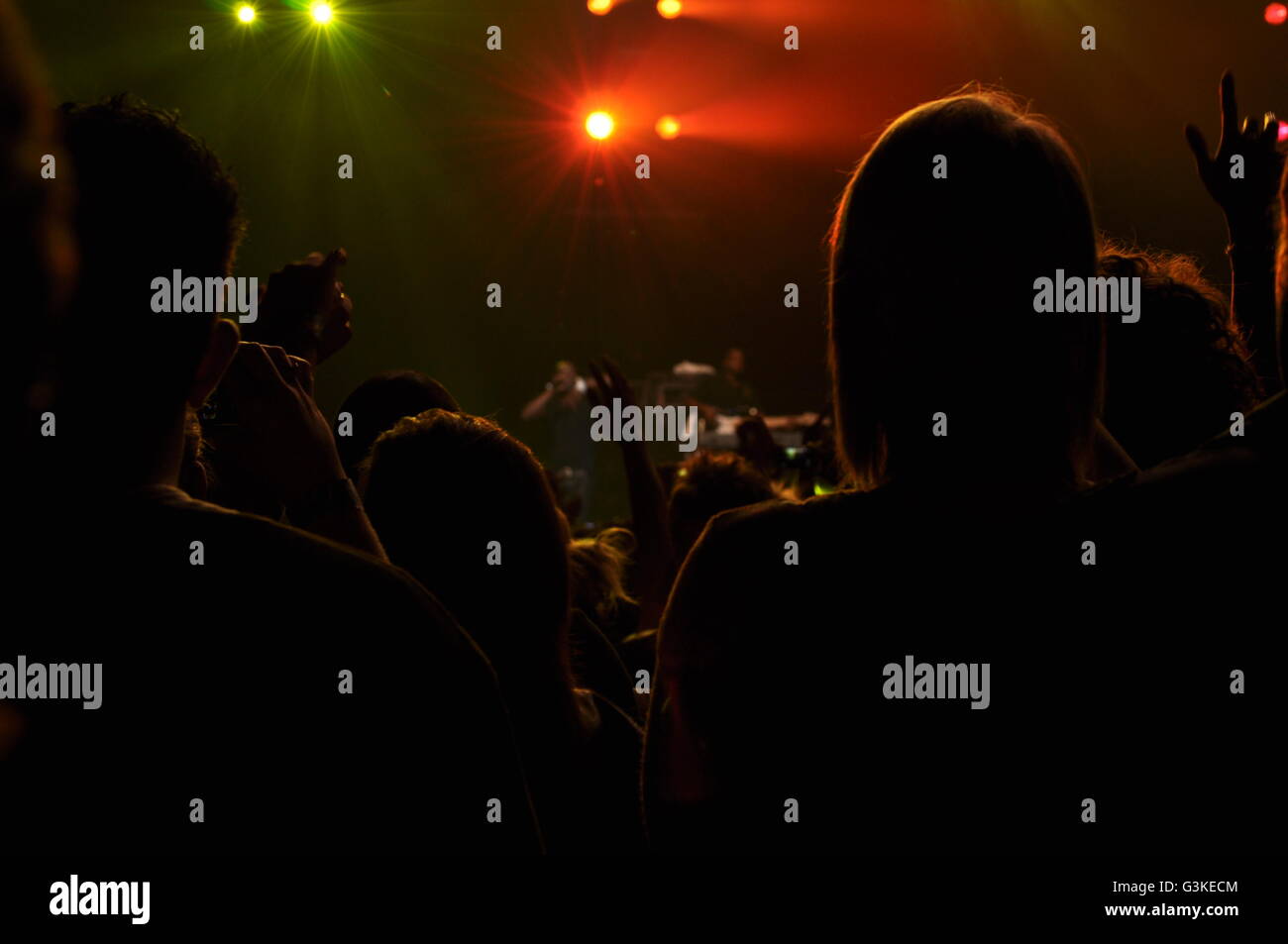 Silhouette of people at a concert with red and green lights shinning from the front Stock Photo