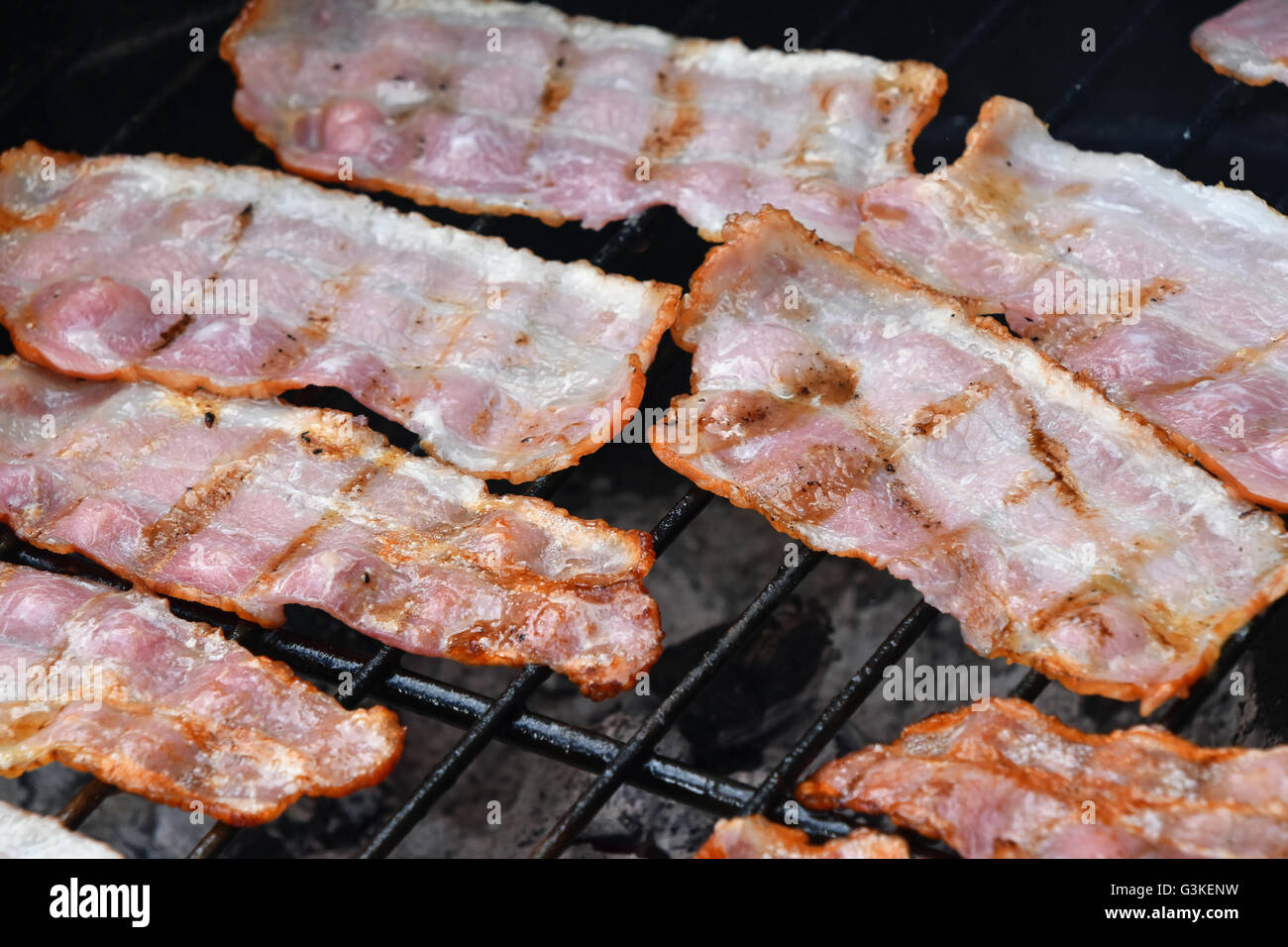 Seceral crispy smoked grilled barbecue bacon slices, cooked on bbq smoke grill, close up Stock Photo