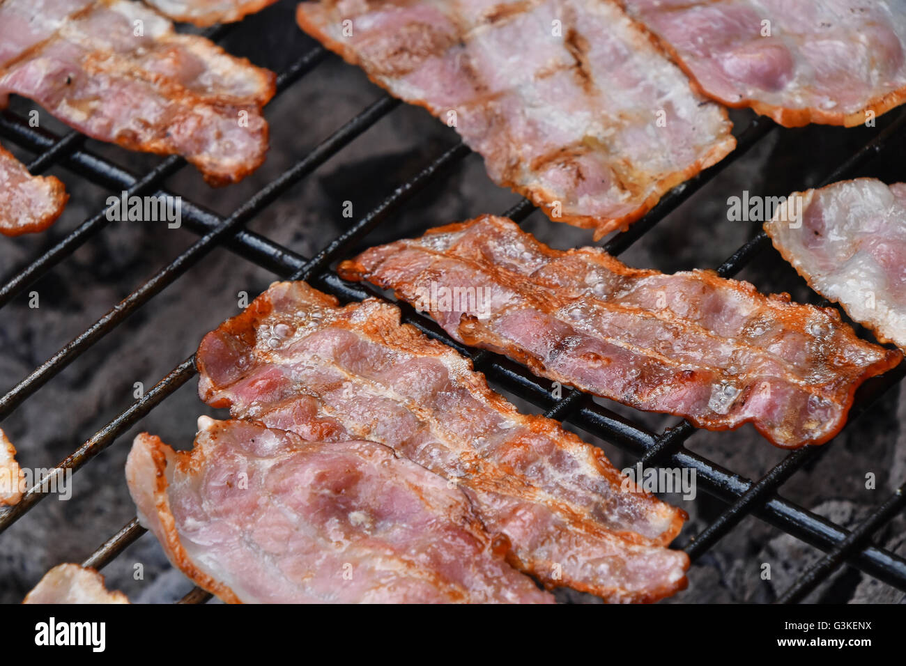 Seceral crispy smoked grilled barbecue bacon slices, cooked on bbq smoke grill, close up Stock Photo