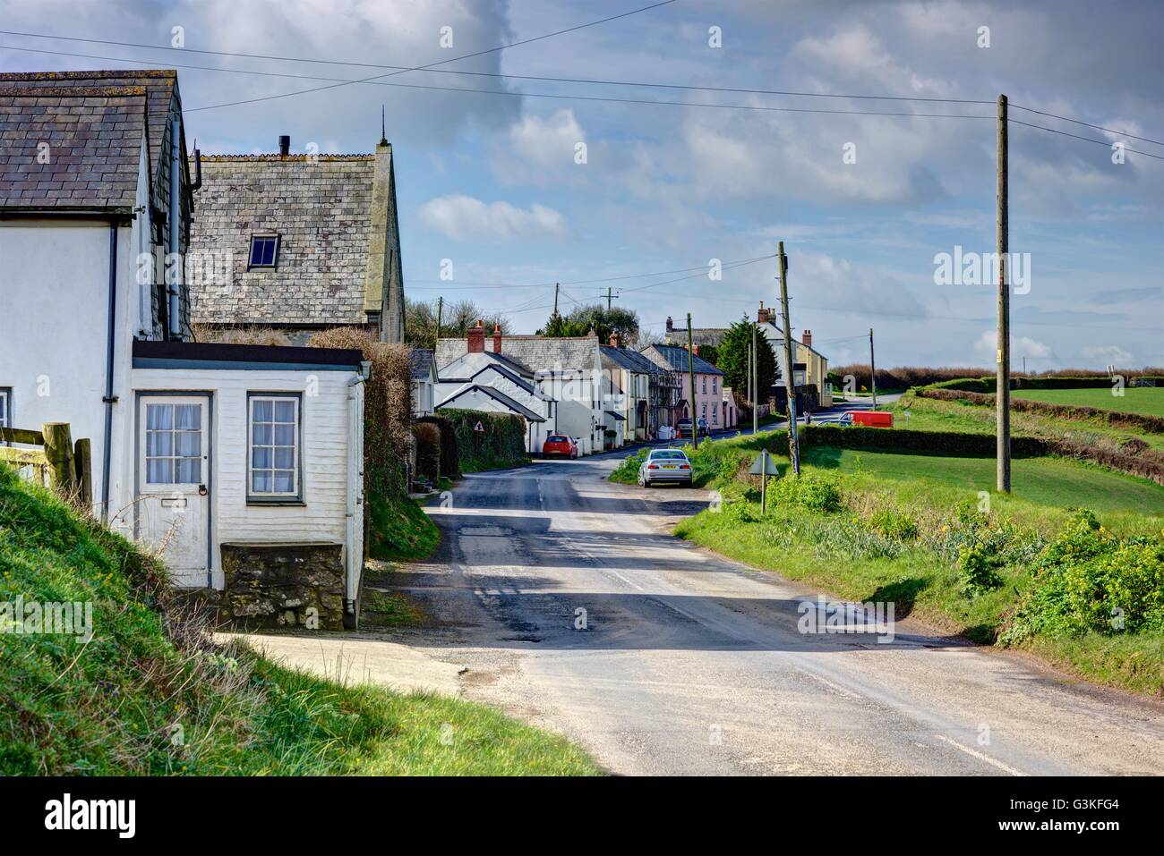 A Cornish village on a bright sunny Spring day showing a single string of colorful cottages on Lanteglos Highway. Blue Sky. Stock Photo