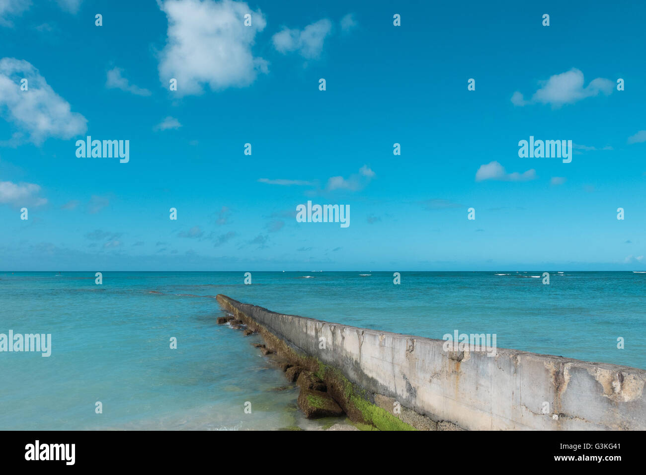 path walk way wall extend to clean blue sea on nice blue cloud sky vacation day. Stock Photo