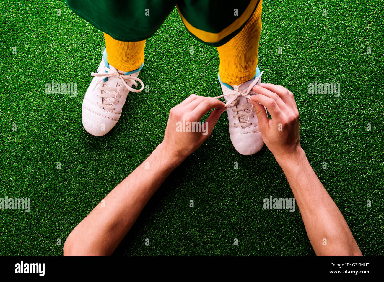 Unrecognizable father tying shoelaces to his son, football Stock Photo