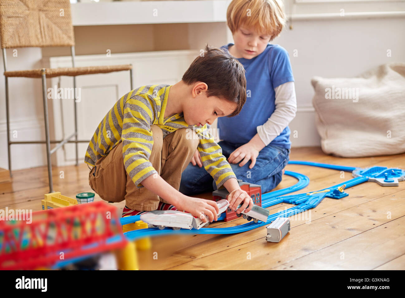 Two young boys playing with toy train set Stock Photo