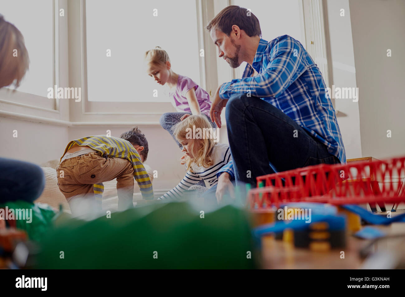 Father watching children play, low angle view Stock Photo