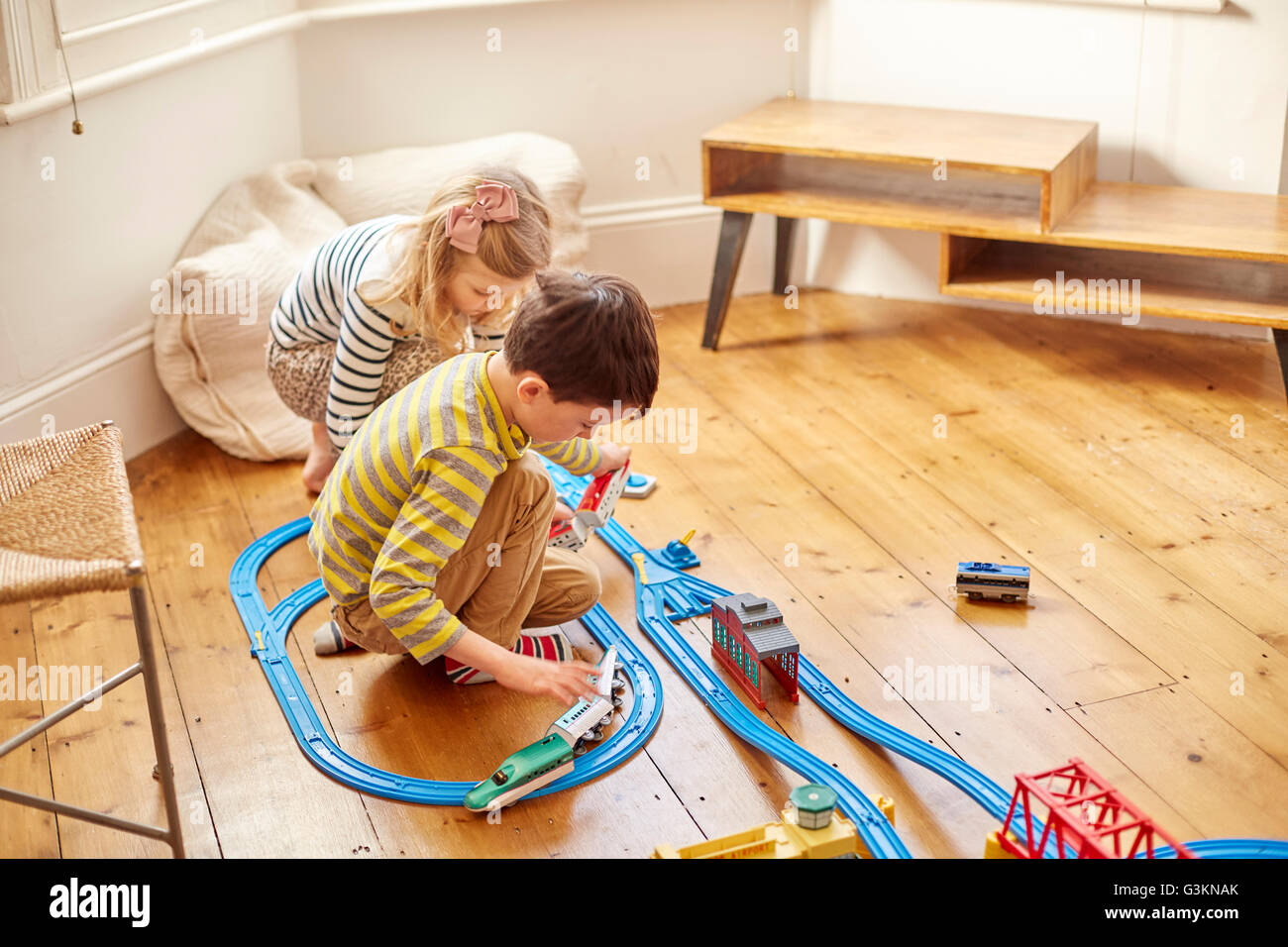 Young girl and boy playing with toy train set Stock Photo