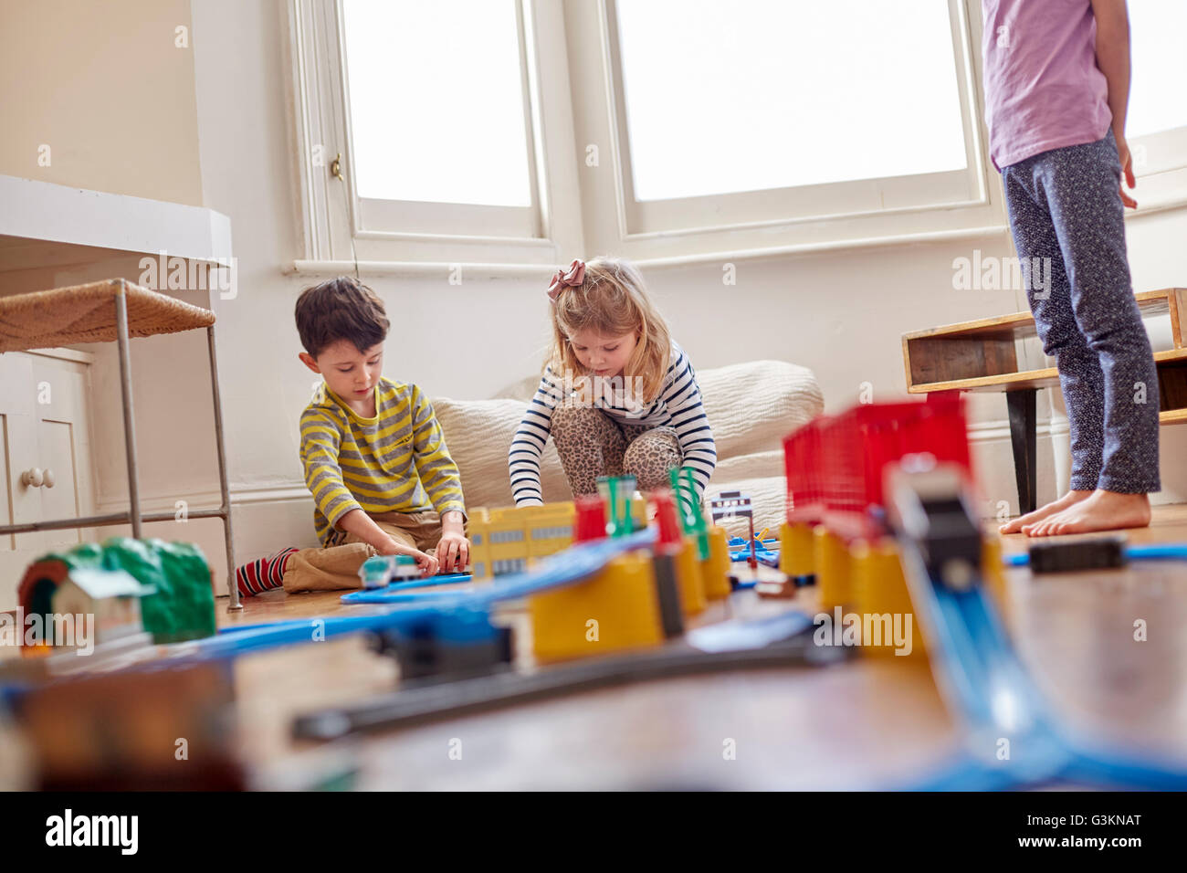 Young children playing with toy train set Stock Photo