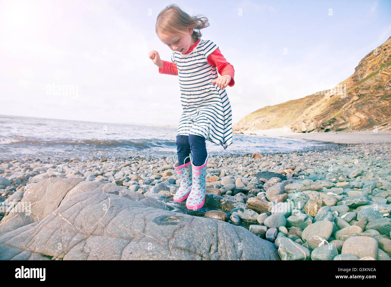 Girl walking on pebbles, Millook Beach, Cornwall Stock Photo