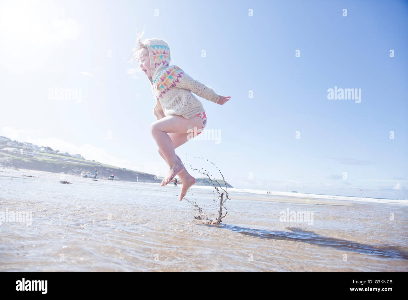 Girl jumping in water, Polzeath Beach, Cornwall Stock Photo