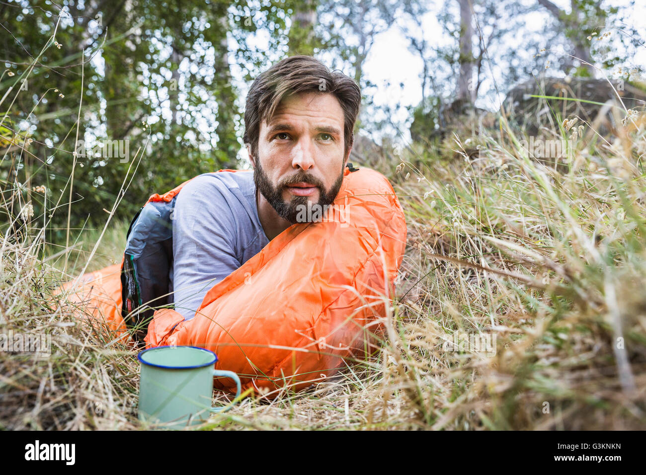 Man watching from sleeping bag in forest, Deer Park, Cape Town, South