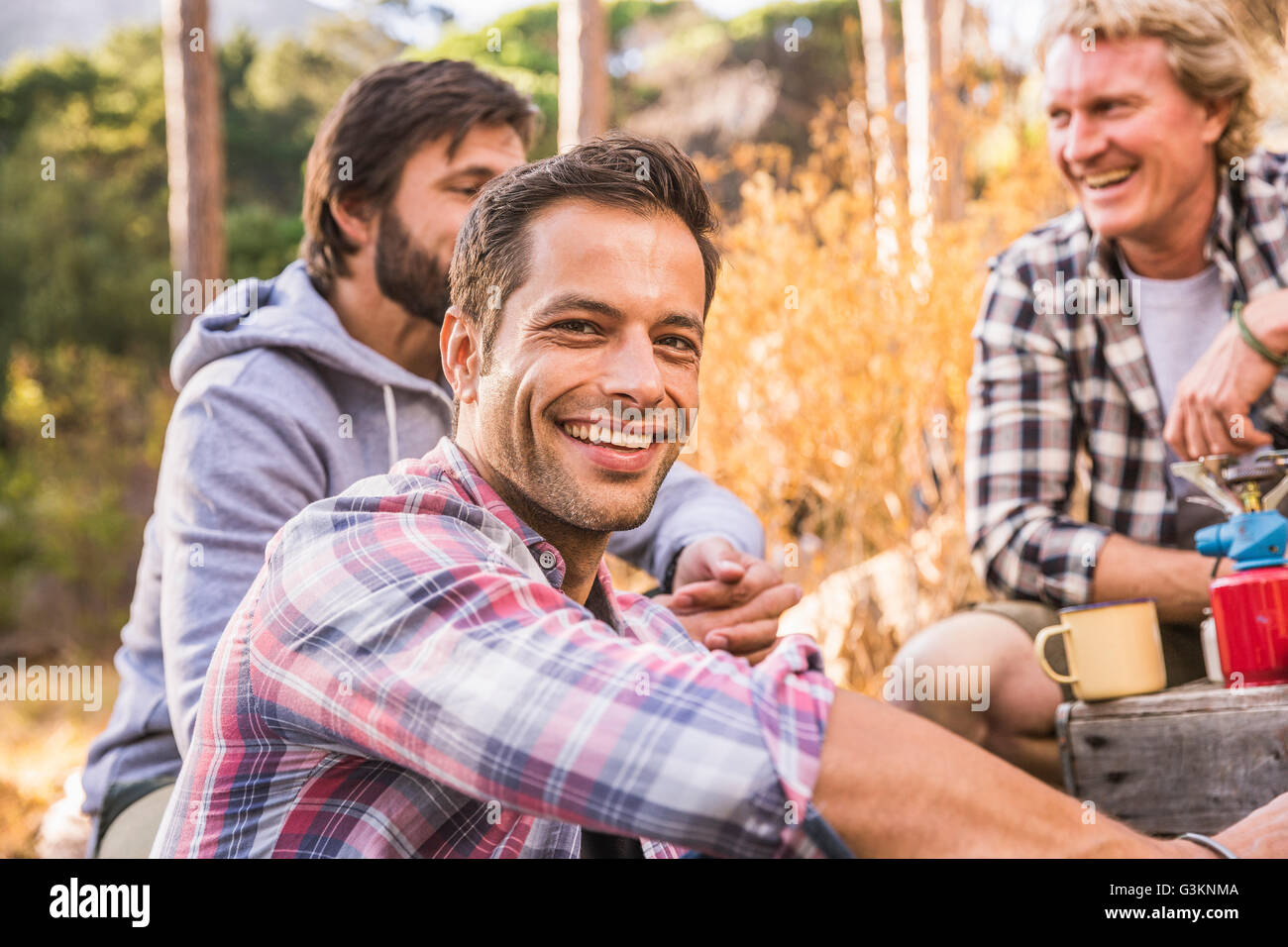 Three men cooking on camping stove in forest, Deer Park, Cape Town, South Africa Stock Photo