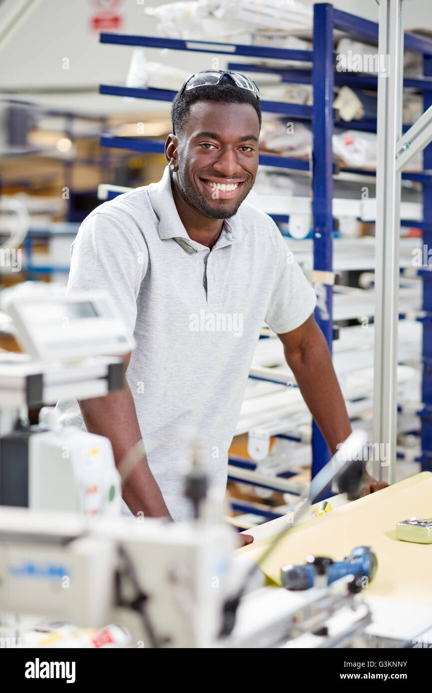 Portrait of young male worker assembling roller blind on production line in factory Stock Photo