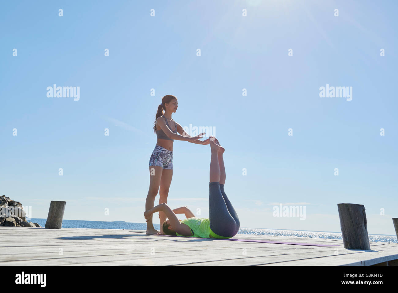 Women on pier holding each others ankles exercising Stock Photo
