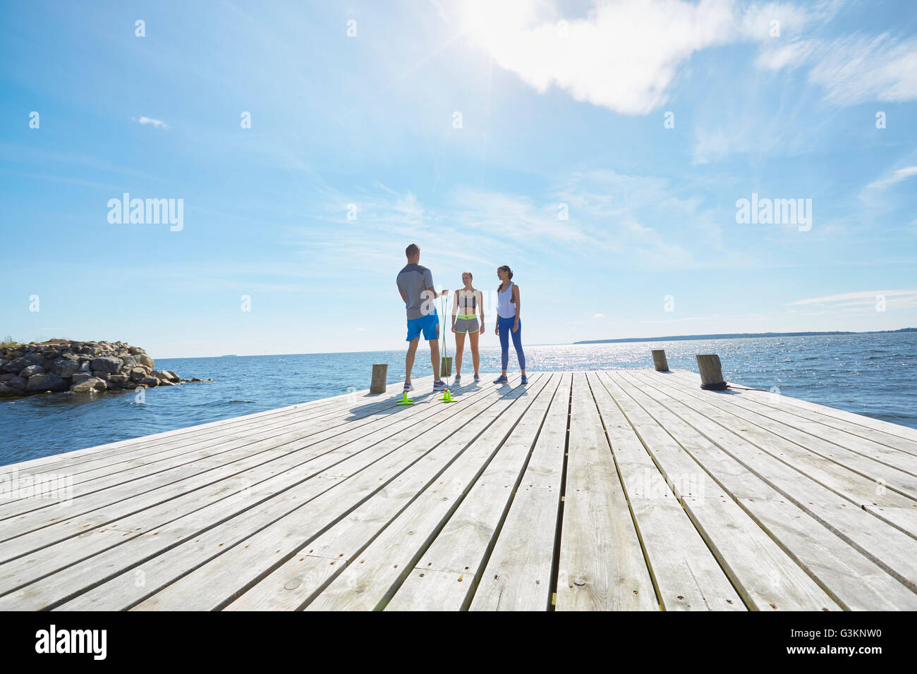 Mid distance view of friends wearing sports clothes standing on pier Stock Photo