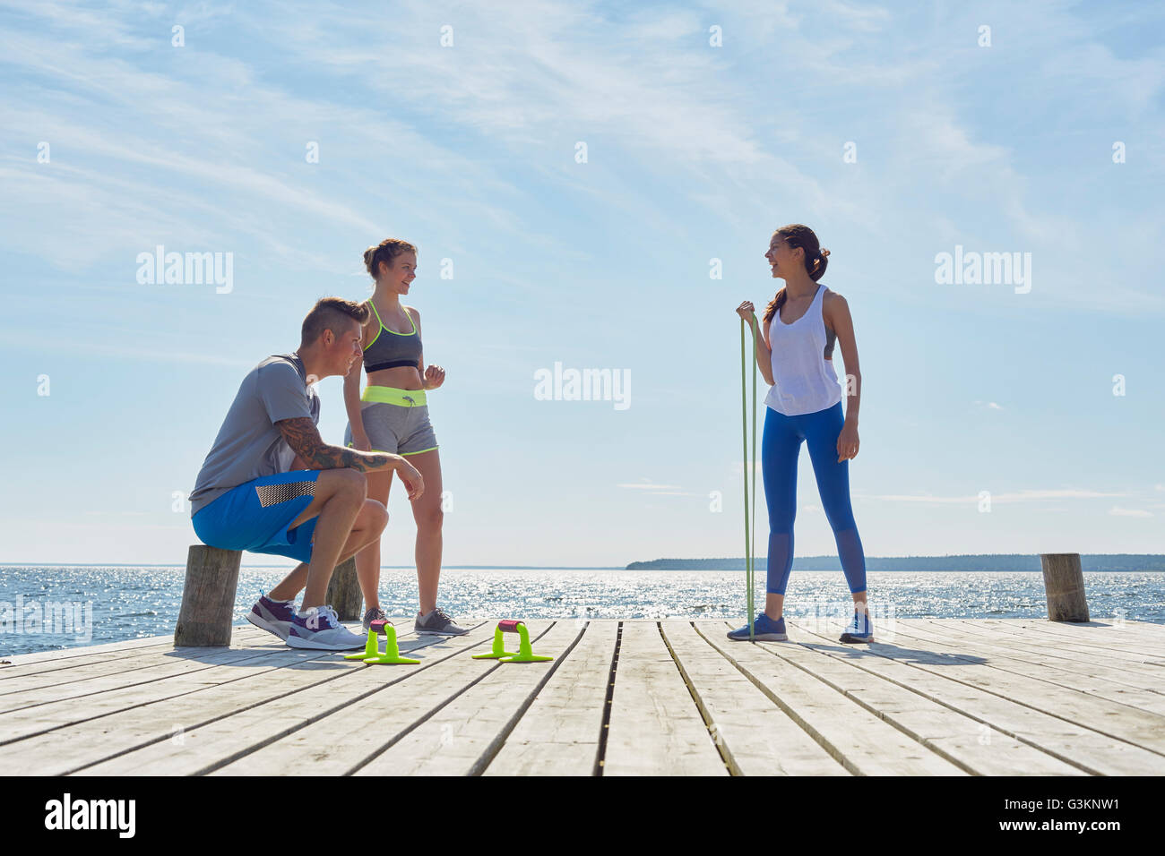 Friends wearing sports clothes on pier with exercise equipment Stock Photo