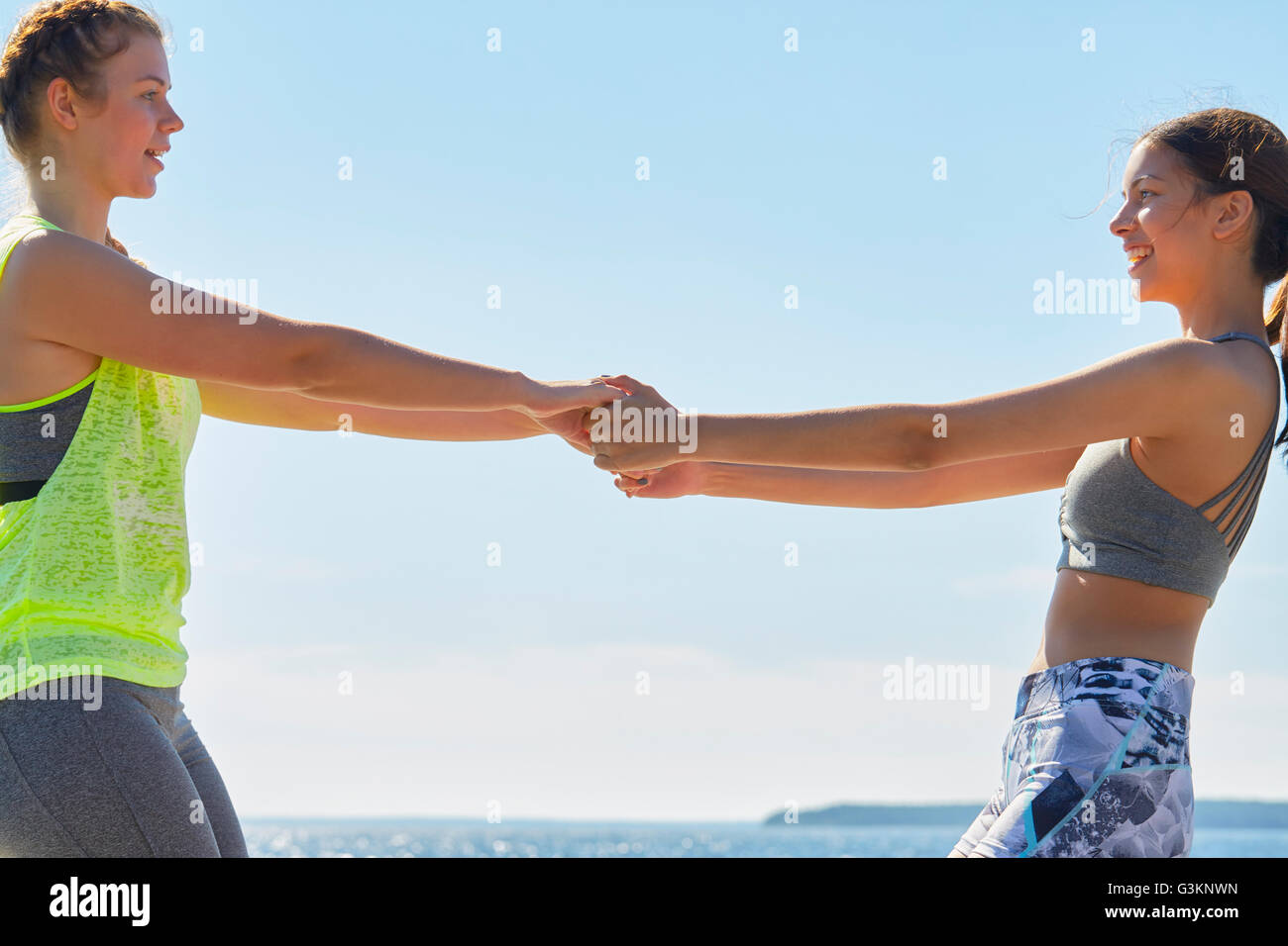 Women wearing sports clothes face to face holding hands smiling Stock Photo