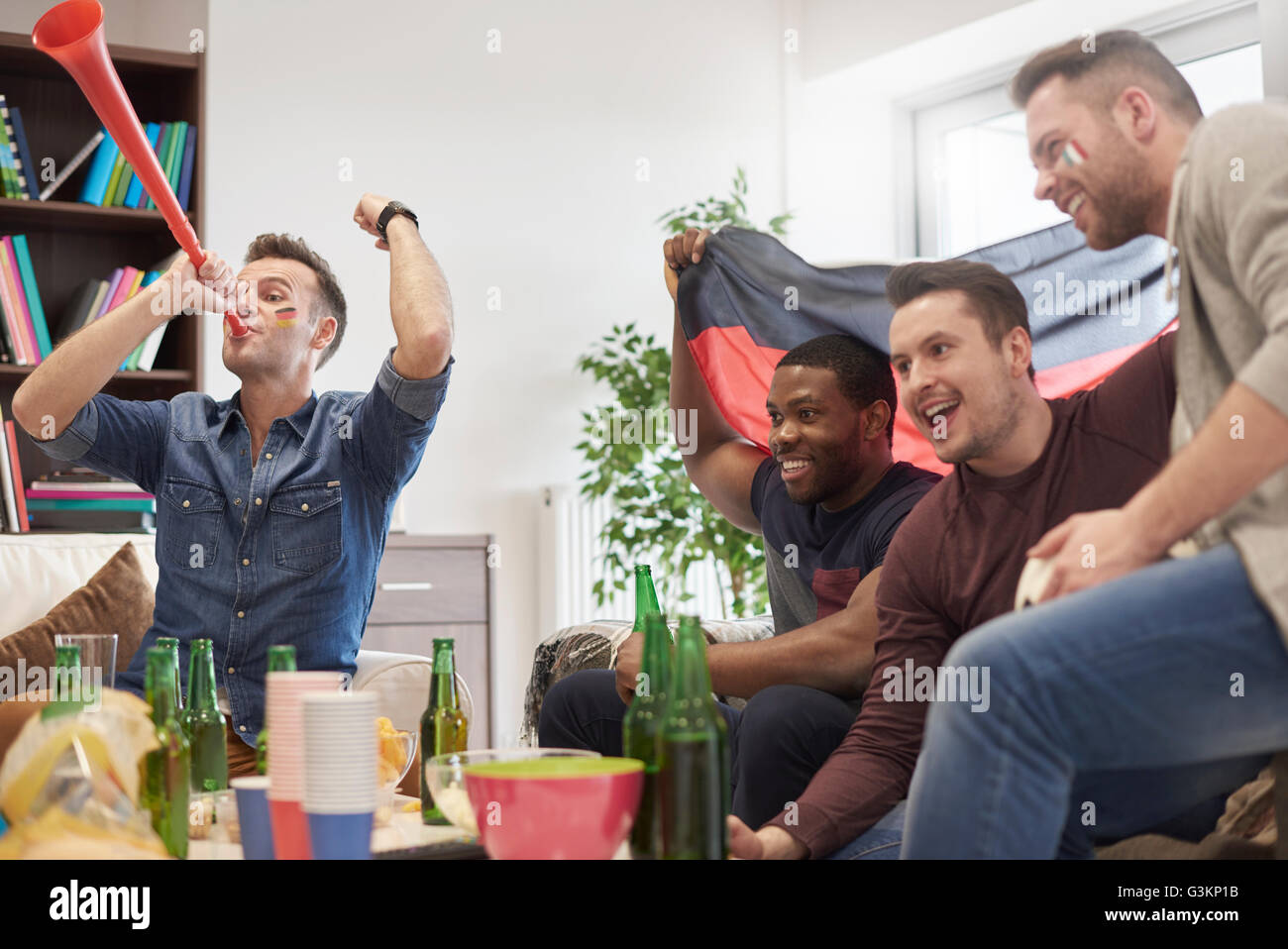 Group of men watching sporting event on television holding German flag