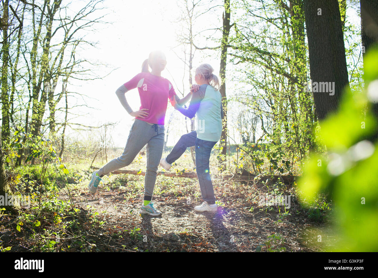 Women in forest face to face legs raised stretching Stock Photo
