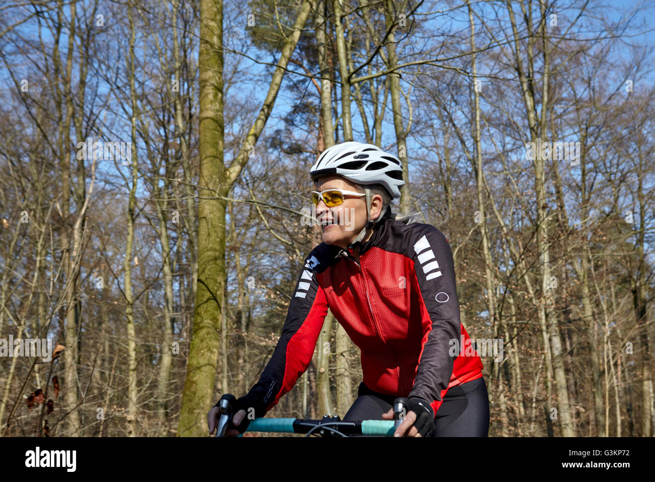 Woman wearing cycling helmet and sunglasses cycling, looking away