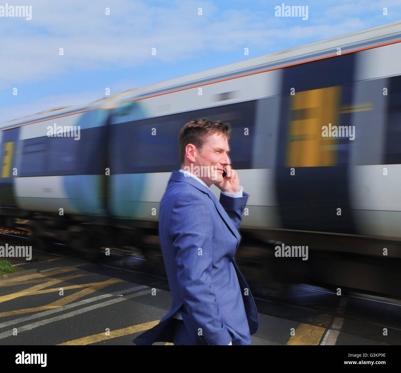 Businessman standing at level crossing, using smartphone Stock Photo