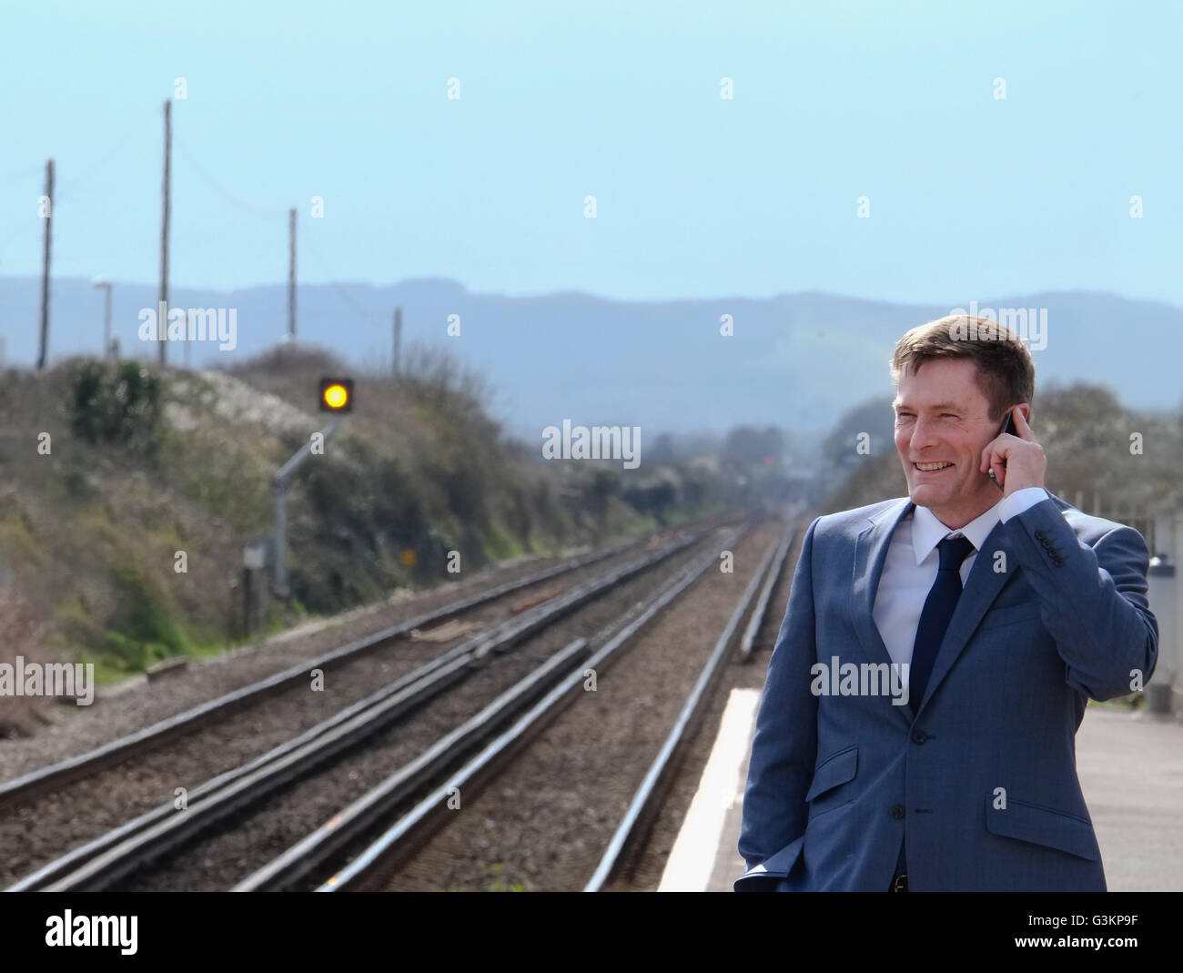 Mature businessman standing on train platform, using smartphone Stock Photo
