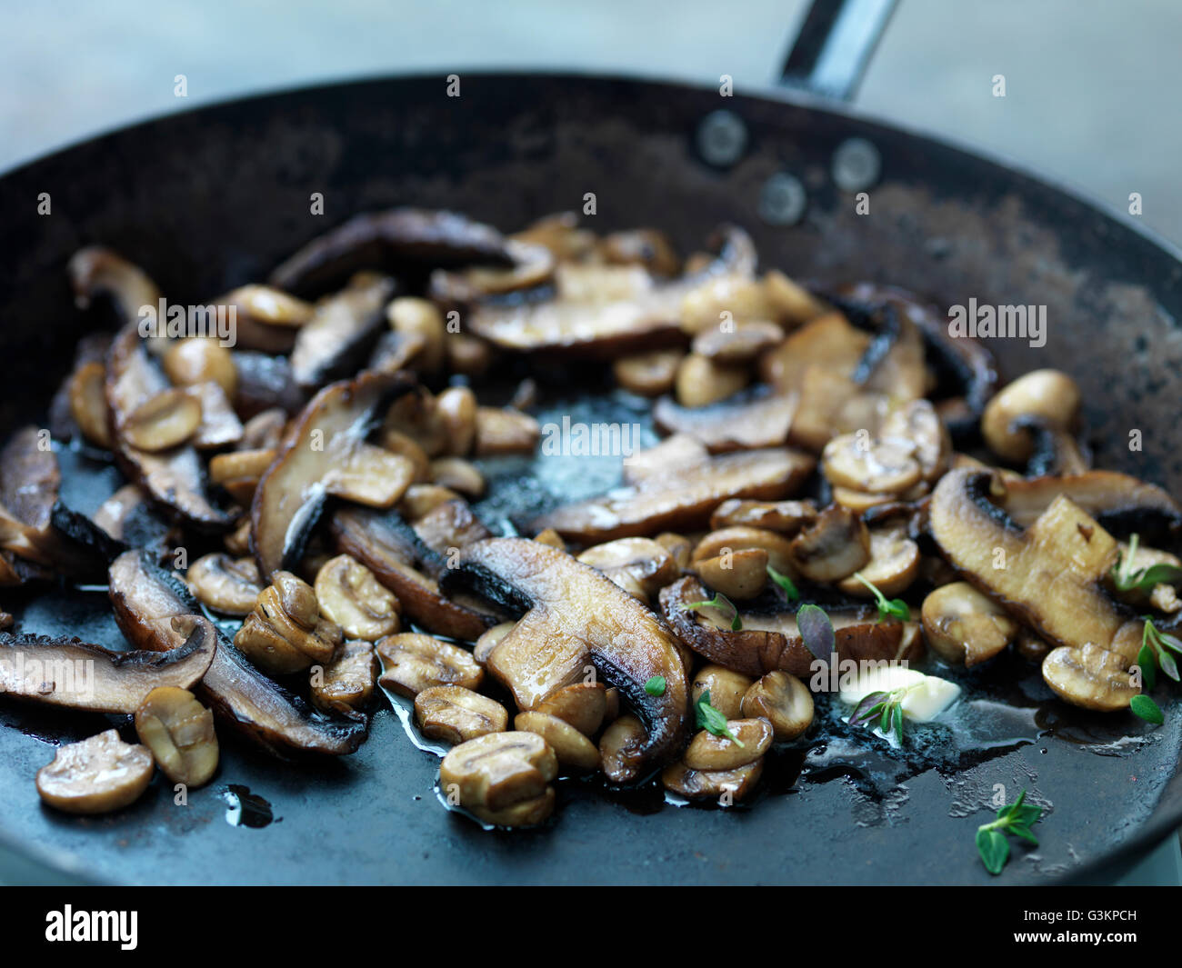 Mushrooms frying in butter in frying pan, close-up Stock Photo