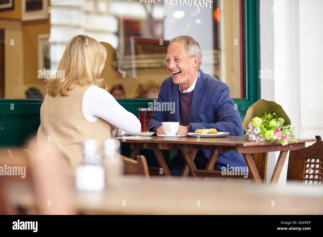 Mature couple on date laughing together at sidewalk cafe table Stock Photo